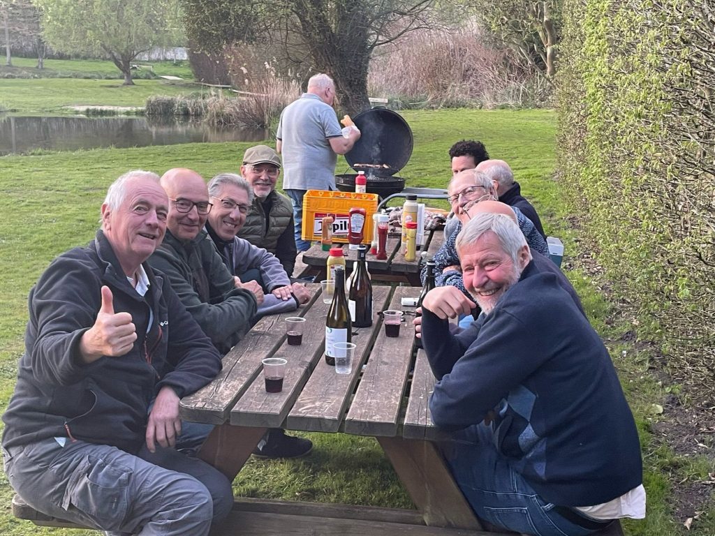 Des membres rient autour d?une table de pique-nique, au bord de l?eau
